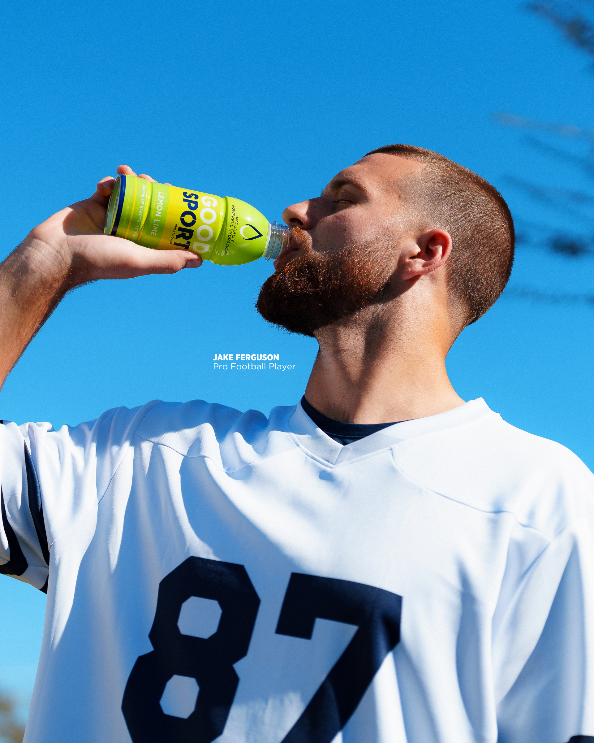 Pro football player Jake Ferguson drinking a bottle of Lemon Lime GoodSport on sidelines.