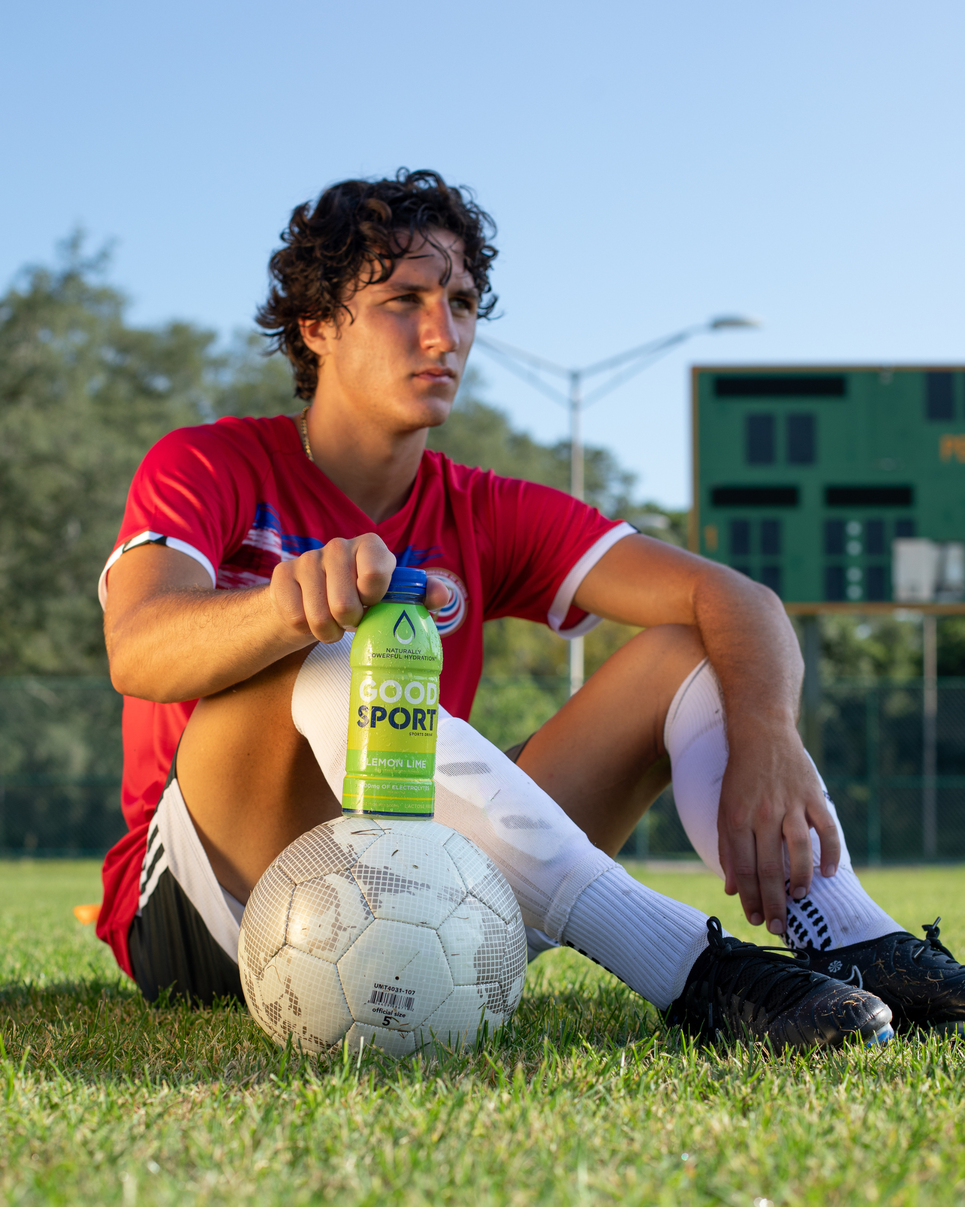 Soccer player holding a bottle of Lemon Lime GoodSport sports drink bottle on a soccer field.